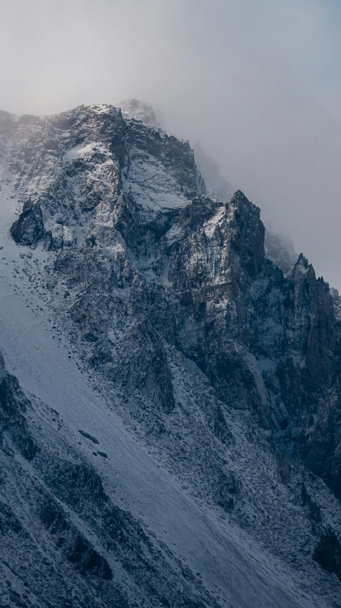 Breathtaking view of snow-covered rocky peaks in Esquel, Argentina, under a cloudy sky.